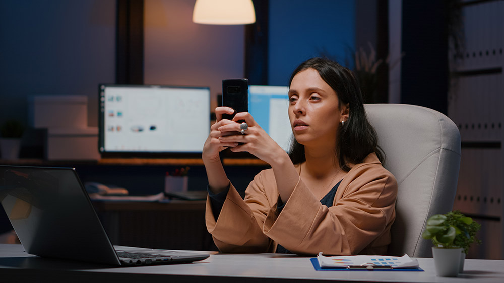 overworked-executive-manager-holding-phone-texting-marketing-ideas-analysing-social-media-strategy-sitting-desk-business-company-office